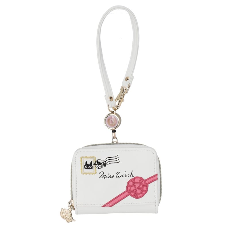 May include: White wallet with a wrist strap, featuring a zipper closure and a decorative charm. The wallet has a design of a black cat, a pink ribbon, and the text "Miss Witch". The wrist strap is white with a gold-colored clasp.