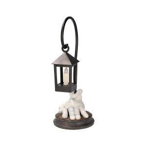 May include: A decorative lantern with a black frame and a faux candle inside. The lantern is suspended from a curved black metal handle and rests above a white hand sculpture. The hand is emerging from a round, textured base.