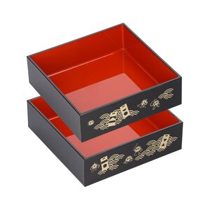 May include: Two black, square bento boxes with red interiors are stacked. The exterior of each box features gold-colored Japanese-style illustrations. The boxes are designed for food storage and transport.