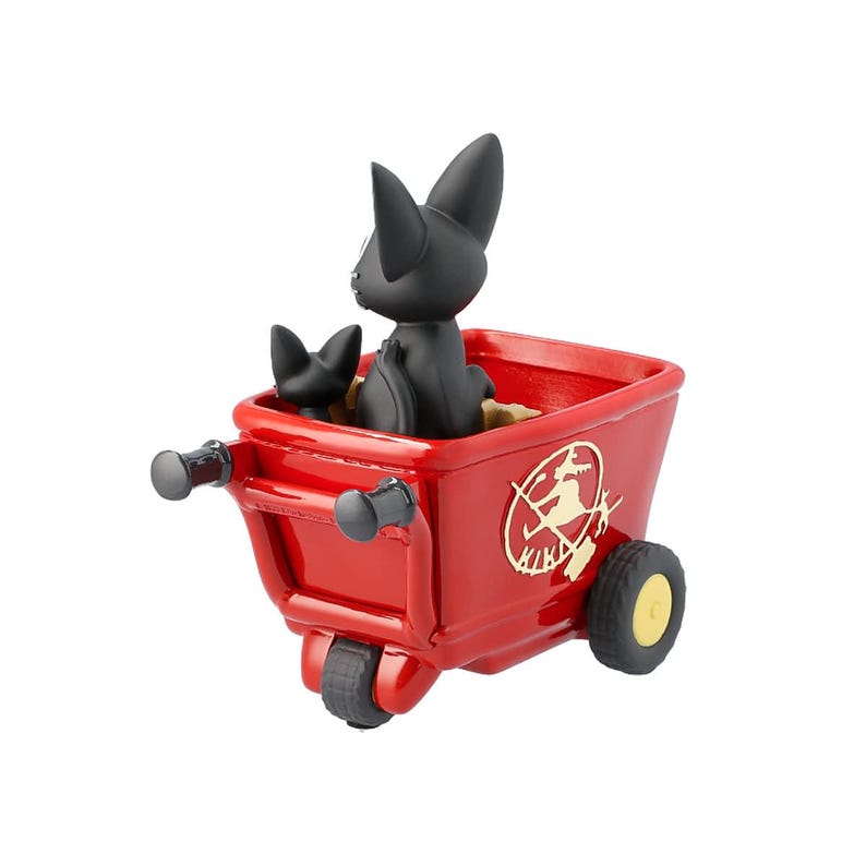 May include: A red toy wagon with a black cat and kitten inside. The wagon has a single front wheel and two small rear wheels. The side of the wagon features a gold emblem with a witch on a broom.