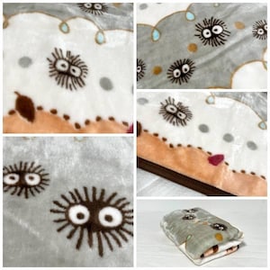 Peut inclure: Une couverture pli&eacute;e avec un motif r&eacute;p&eacute;t&eacute; de cr&eacute;atures de dessins anim&eacute;s aux grands yeux et aux corps &eacute;pineux. La couverture a une palette de couleurs grise, blanche et marron avec une texture douce et moelleuse. Le design comprend des accents marron, gris et bleu clair.