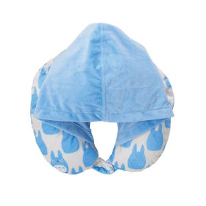May include: A blue travel pillow with a hood. The hood and the top of the pillow are a solid light blue. The bottom of the pillow has a white background with blue cartoon character designs. The pillow is designed to be worn around the neck.