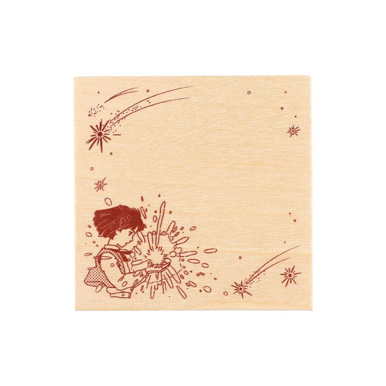 May include: A square wooden rubber stamp featuring a dark red engraved illustration of a person with short hair holding a glowing, star-like burst of light. The design includes scattered stars and shooting star trails across the light wood surface.