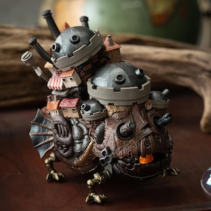 May include: A detailed, steampunk-inspired figurine of a creature with a fortress on its back. The figure features a brown and bronze color scheme, with miniature houses, turrets, and mechanical details. The creature has fin-like structures and clawed feet.