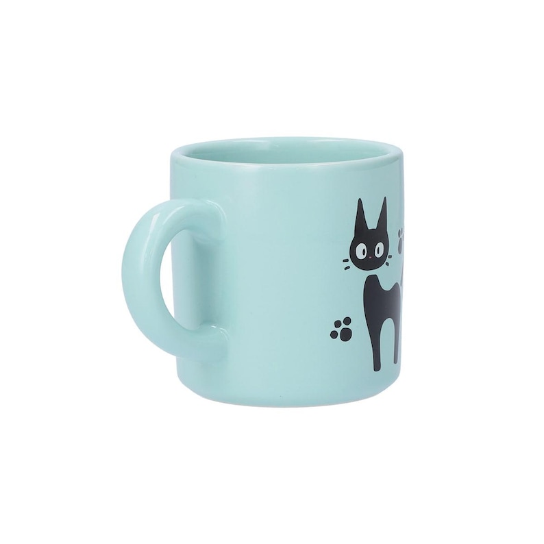 May include: A light blue ceramic mug featuring a black graphic illustration of a cat with large eyes and pointed ears. The design includes small black paw prints surrounding the cat figure, set against the solid pastel blue surface of the mug.