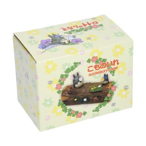 May include: A decorative accessory case featuring characters from the animated film "My Neighbor Totoro." The box is light yellow with a floral pattern. The front of the box has a wooden log with Totoro and other characters.