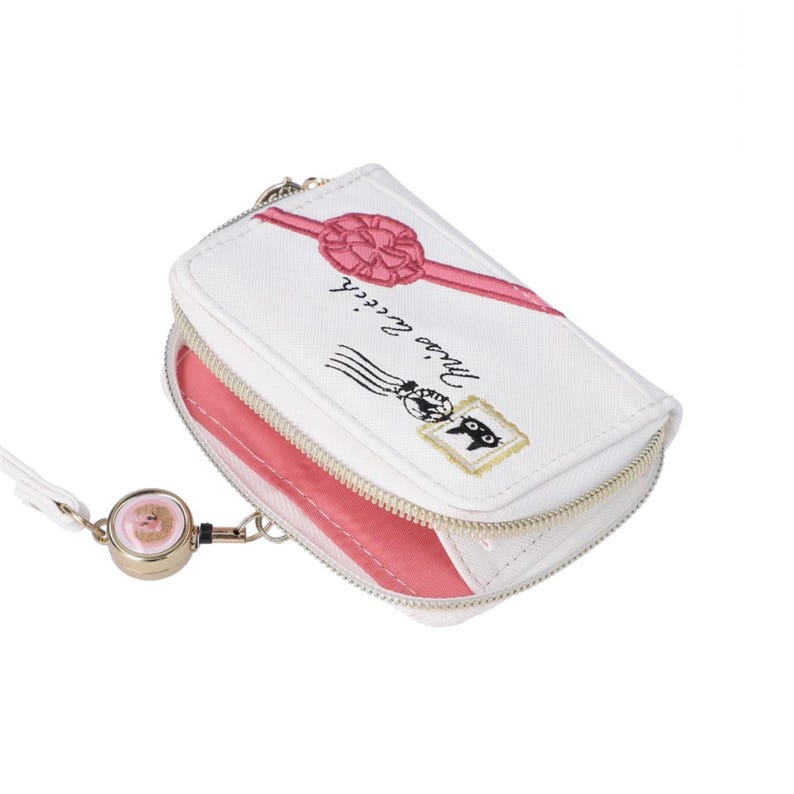 May include: White zippered wallet with a pink interior, featuring a pink bow and ribbon design. The wallet has a cat postage stamp illustration and the text "Miss la cicich". Includes a retractable key chain.