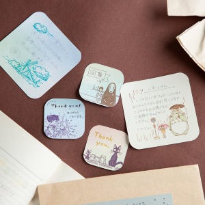 May include: A collection of five square memo pads with rounded corners, featuring various Studio Ghibli character illustrations and Japanese text. The designs include Totoro with an umbrella, No-Face, and Jiji the cat, printed on light-colored paper.