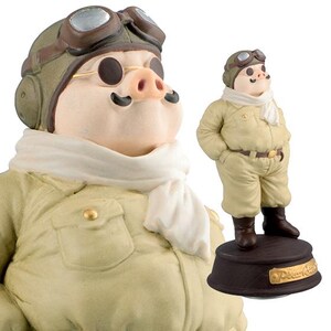 May include: A pig figurine dressed as a pilot, wearing a khaki flight suit, aviator goggles, and a white scarf. The pig has a pink snout and black moustache. The figurine is on a dark brown base.