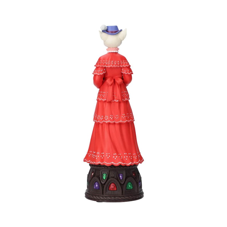 Puede incluir: Figura de un gato blanco con un vestido rojo y un sombrero azul. El vestido tiene un dise&ntilde;o escalonado con detalles florales blancos. La base es marr&oacute;n oscuro con incrustaciones coloridas en forma de joya. El gato est&aacute; de espaldas al espectador.