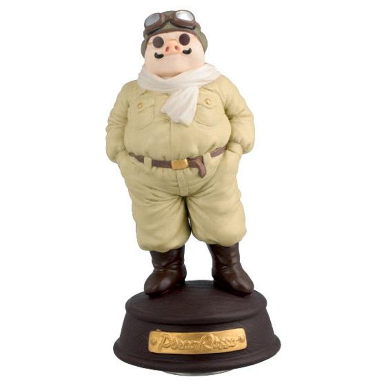 May include: A figurine of a pig in a pilot's outfit, featuring a tan jumpsuit, goggles, and a white scarf. The pig stands on a brown base with gold lettering that reads "Porco Rosso". The figurine has brown boots and a brown belt.