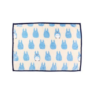 May include: A rectangular, cream-colored blanket featuring a repeating pattern of light blue cartoon characters. The blanket has a dark blue border. The cartoon characters have white bellies and are in various poses.