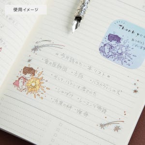 May include: An open notebook with lined pages featuring handwritten Japanese text and colorful illustrations of a person holding a glowing light. A silver fountain pen rests at the top. A blue sticker with the text Thank you is visible.