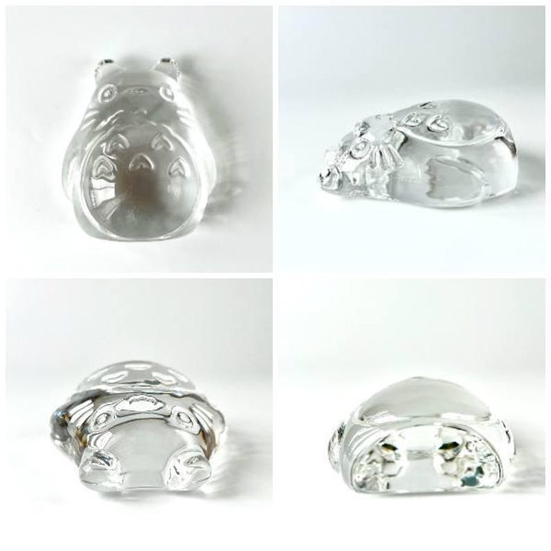 May include: Four clear glass figurines of a cartoon character. The figurines are in different poses, including standing and lying down. The glass is transparent, allowing light to pass through, and the details of the character are visible.