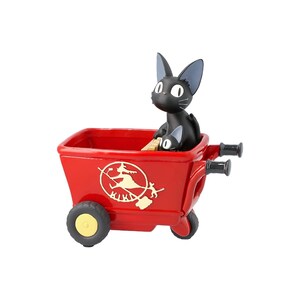 May include: A red wheelbarrow with a black cat figurine inside. The wheelbarrow has black handles and yellow wheels. A logo of a witch on a broom is on the side of the wheelbarrow.