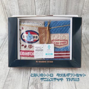 Puede incluir: Un juego de regalo en caja con dos toallas con el tema Mi Vecino Totoro. Una toalla es beige con un gr&aacute;fico de Totoro y el texto "EIGHBOR". La otra es azul con un parche "Since 1988". Incluye una etiqueta que dice "TOTORO".