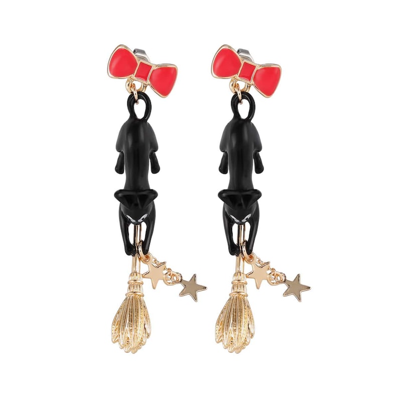May include: A pair of dangle earrings featuring a red bow, a black cat, a gold-colored broom, and gold stars. The earrings are designed with a whimsical, Halloween theme.