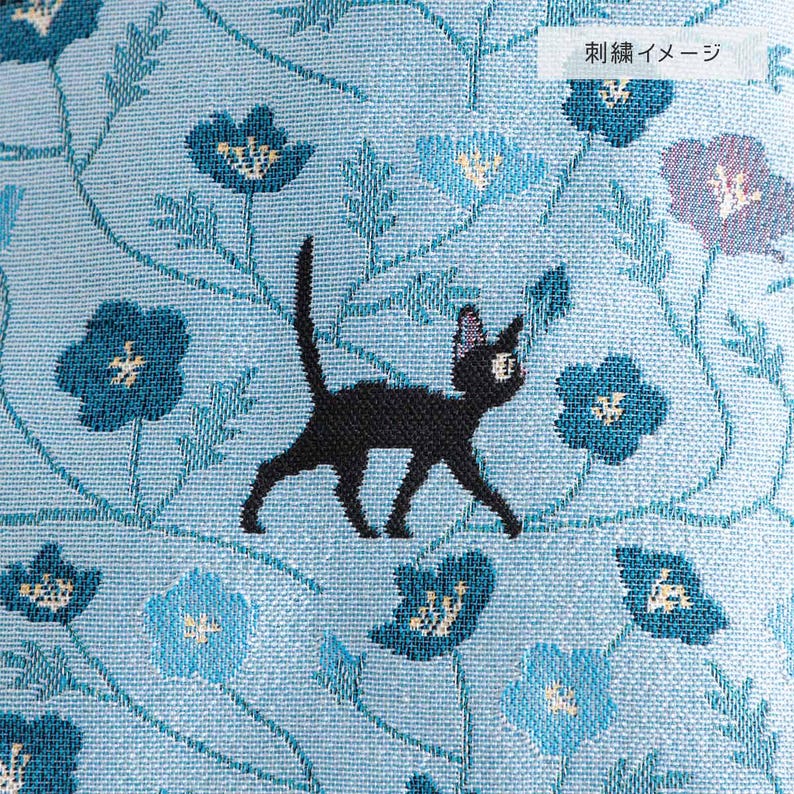 May include: A blue fabric with a black cat walking through a field of blue flowers. The fabric has the text "fabric sample" in Japanese.