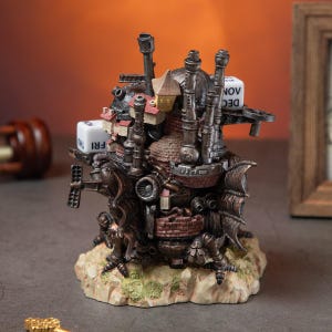 May include: A detailed, steampunk-style figurine of a fantastical building with chimneys, turrets, and wings. The sculpture features a weathered, metallic finish with red brick accents and a small house on top. Dice with the days of the week and months are attached.