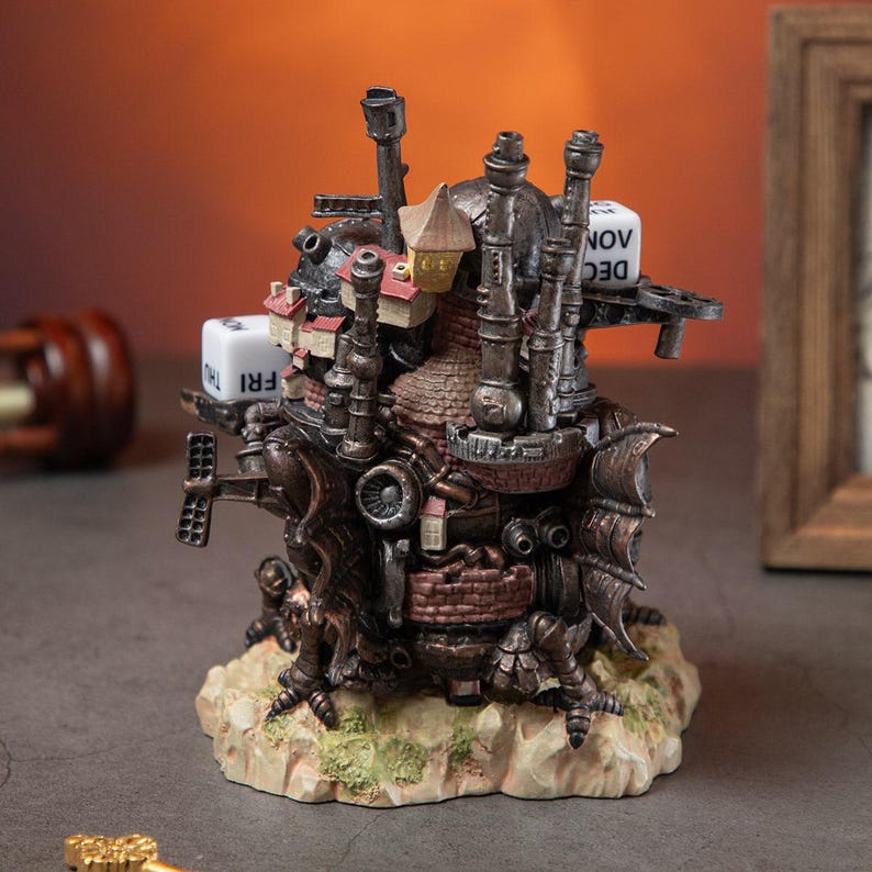 May include: A detailed, steampunk-style figurine of a fantastical building with chimneys, turrets, and wings. The sculpture features a weathered, metallic finish with red brick accents and a small house on top. Dice with the days of the week and months are attached.