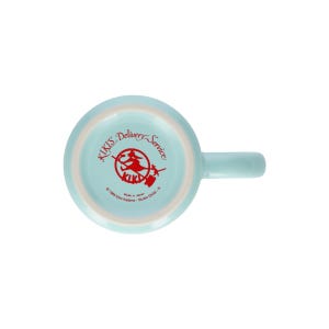 May include: A light blue ceramic mug viewed from the bottom, featuring a red graphic of a character on a broomstick. The text reads Kiki's Delivery Service, 1989 Eiko Kadono - Studio Ghibli - N, and Made in Japan, printed in red on the base.