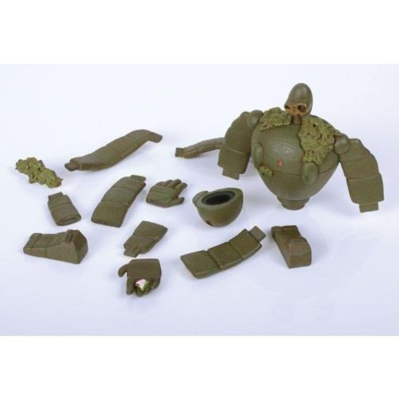 Peut inclure: Une figurine de robot vert olive d&eacute;mont&eacute;e avec diverses pi&egrave;ces d&eacute;tach&eacute;es, dont des bras, des jambes et une t&ecirc;te. Le corps du robot est rond et la t&ecirc;te a un casque. Certaines pi&egrave;ces ont une texture semblable &agrave; de la mousse.