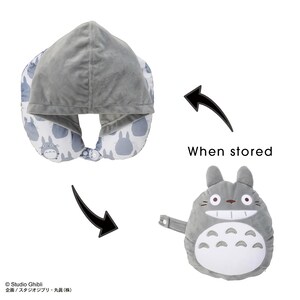 May include: A gray travel pillow with a hood, featuring a pattern of cartoon characters. The pillow transforms into a plush Totoro character when stored. The text "When stored" is also visible.