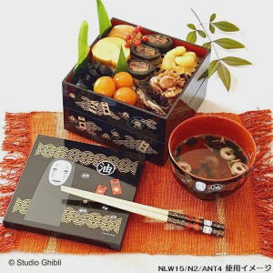 May include: A Japanese bento box with various food items, including eggs, black beans, and orange fruits. The box is black with gold wave patterns. A matching bowl of soup and a box with a character illustration are also present, along with chopsticks.
