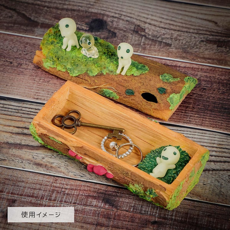 Pode incluir: Duas bandejas decorativas de madeira com tema da natureza. Uma bandeja cont&eacute;m uma chave e an&eacute;is vintage, a outra tem tr&ecirc;s pequenas figuras em um tronco. As bandejas s&atilde;o marrons com detalhes verdes e rosa, em uma superf&iacute;cie de madeira.