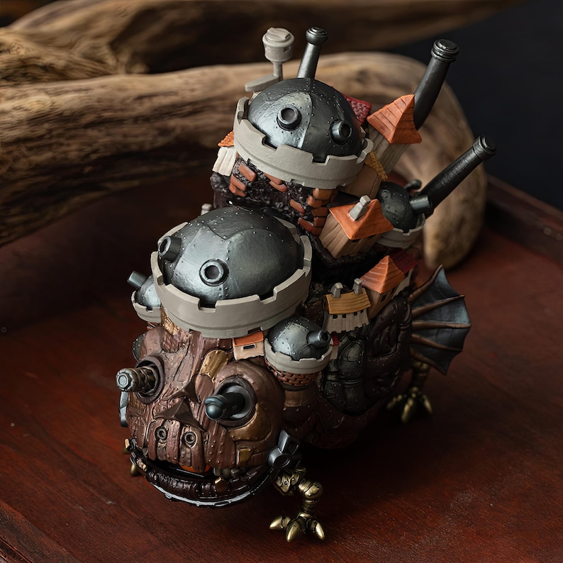 May include: A detailed, fantasy-themed figurine featuring a multi-layered design. The figurine has a dark brown, textured base with metallic accents and two dome-shaped structures on top, each with small, orange-roofed buildings. Cannons and fins add to the intricate details.