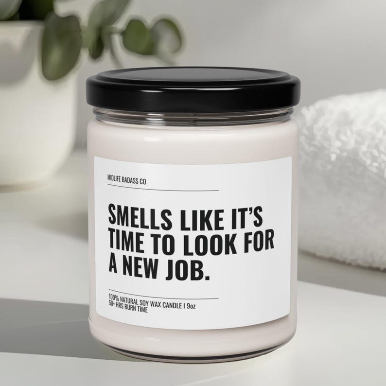 Pode incluir: Uma vela branca num frasco de vidro com tampa preta. O r&oacute;tulo diz "SMELLS LIKE IT'S TIME TO LOOK FOR A NEW JOB." A vela tem 255g e um tempo de queima de 50 horas. A marca &eacute; "MIDLIFE BADASS CO."