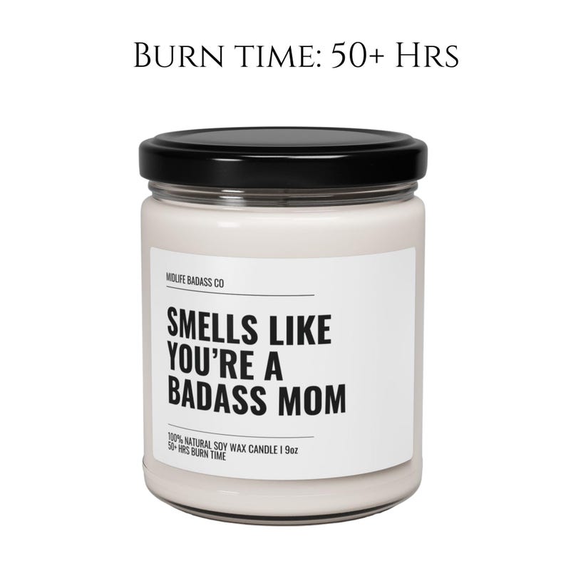 May include: A white candle jar with a black lid and label. The label reads "Smells Like You're A Badass Mom" and "100% Natural Soy Wax Candle | 9oz | 50+ Hrs Burn Time".