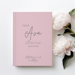 Puede incluir: Un diario rosa pálido con el texto "DEAR Ava LETTERS TO MY DAUGHTER All the things I wish I could tell you." El diario está junto a peonías blancas con hojas verdes.