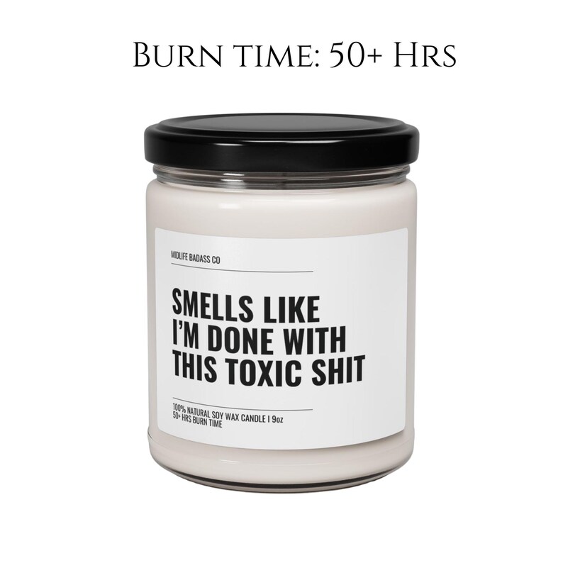 May include: A white candle jar with a black lid and label. The label reads "Smells Like I'm Done With This Toxic Shit" and "Midlife Badass Co". The candle is 100% natural soy wax and has a burn time of 50+ hours.