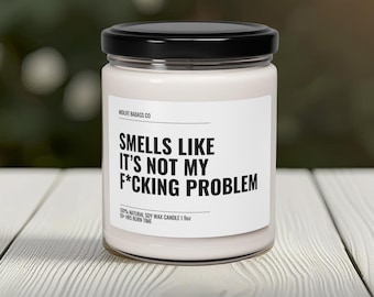 Op de afbeelding: Een witte sojawas kaars met een zwart label waarop staat "Smells Like It's Not My F*cking Problem". De kaars is 9 oz en heeft een brandtijd van 50 uur.