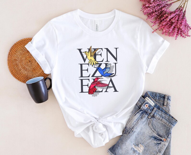 May include: White t-shirt with a graphic of hummingbirds and the word "VENEZUELA" printed on it.