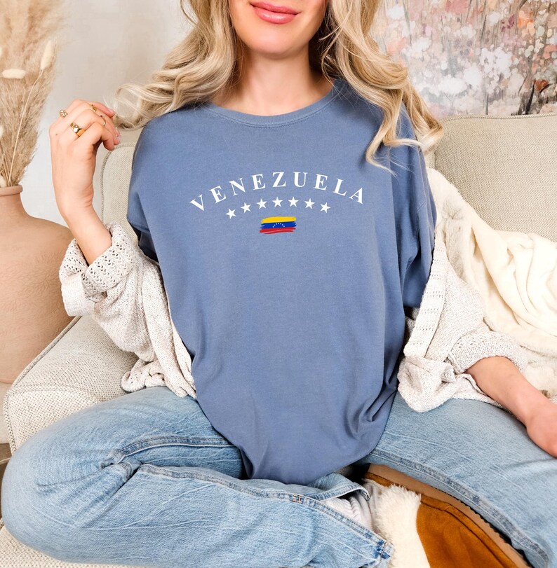 Pode incluir: Uma camiseta azul com a palavra "VENEZUELA" em letras brancas e um pequeno gr&aacute;fico da bandeira venezuelana.