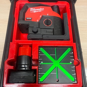 May include: A red and black Milwaukee laser level in a red plastic case with a green laser target. The case has a compartment for a battery.