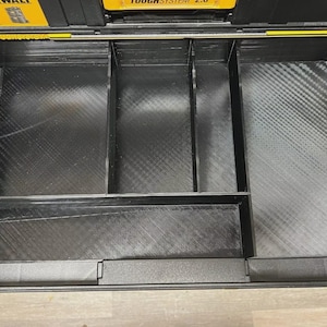 Könnte beinhalten: Schwarzer Kunststoff-Organizer-Einsatz für eine Werkzeugkiste. Der Einsatz hat mehrere unterschiedlich große Fächer zur Aufnahme von Werkzeugen und Zubehör. Der Organizer ist für die DeWalt ToughSystem 2.0 Werkzeugbox konzipiert.