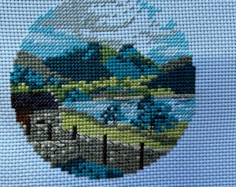 completed cross stitch of a countryside scene