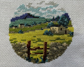 completed cross stitch of a countryside scene