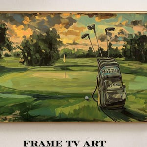 May include: A framed painting of a golf course at sunset. The artwork features a green golf course with a flag, a golf ball, and a golf bag with the text "BEST DAD BY PAR". The sky is a mix of orange and yellow.