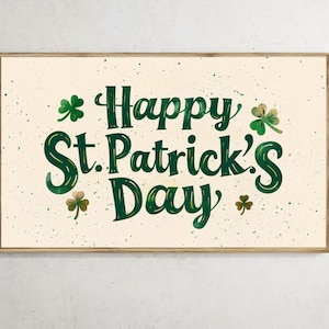 May include: A framed print with the text "Happy St. Patrick's Day" in dark green, decorated with shamrocks. The background is a light beige with green speckles, and the frame is a light brown.