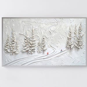 Könnte beinhalten: Weißes, strukturiertes Kunstwerk, das eine verschneite Skipiste mit mehreren Tannen zeigt. Zwei Skifahrer in Rot und Blau fahren die Piste hinunter. Das Kunstwerk ist in einem silbernen Rahmen gerahmt.