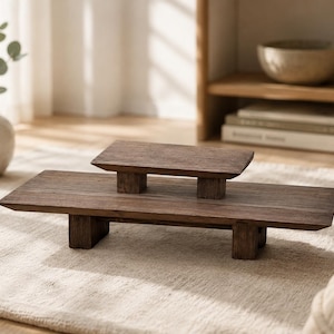 Peut inclure: Un plateau de service ou présentoir en bois brun foncé à deux niveaux. Le niveau inférieur est rectangulaire, avec un niveau supérieur carré plus petit. Le support est en bois massif et a un aspect naturel et rustique.