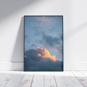 May include: A framed photograph of a large, fluffy, orange-hued cloud against a blue sky.