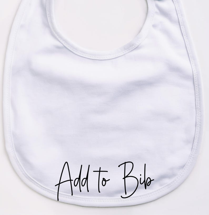 May include: A white baby bib with rounded edges. The bib has the words "Add to Bib" in black script across the bottom. The bib is made of a soft, absorbent material.
