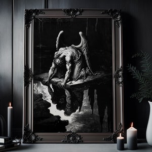 以下が含まれることがあります： 翼のある堕天使が岩の塊の上にひざまずいている、白黒の額装されたプリント。天使は水たまりに映る自分の姿を下に見つめている。