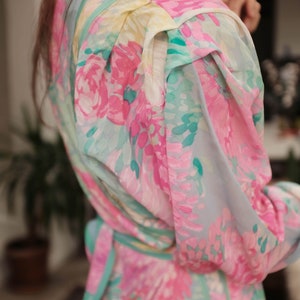 May include: A light blue dress with a floral print in shades of pink, green, and white. The dress has a cinched waist and a ruffled neckline.
