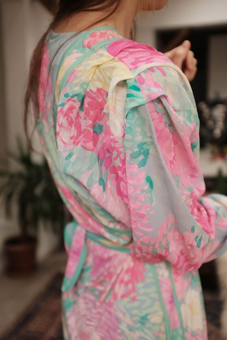 May include: A light blue dress with a floral print in shades of pink, green, and white. The dress has a cinched waist and a ruffled neckline.